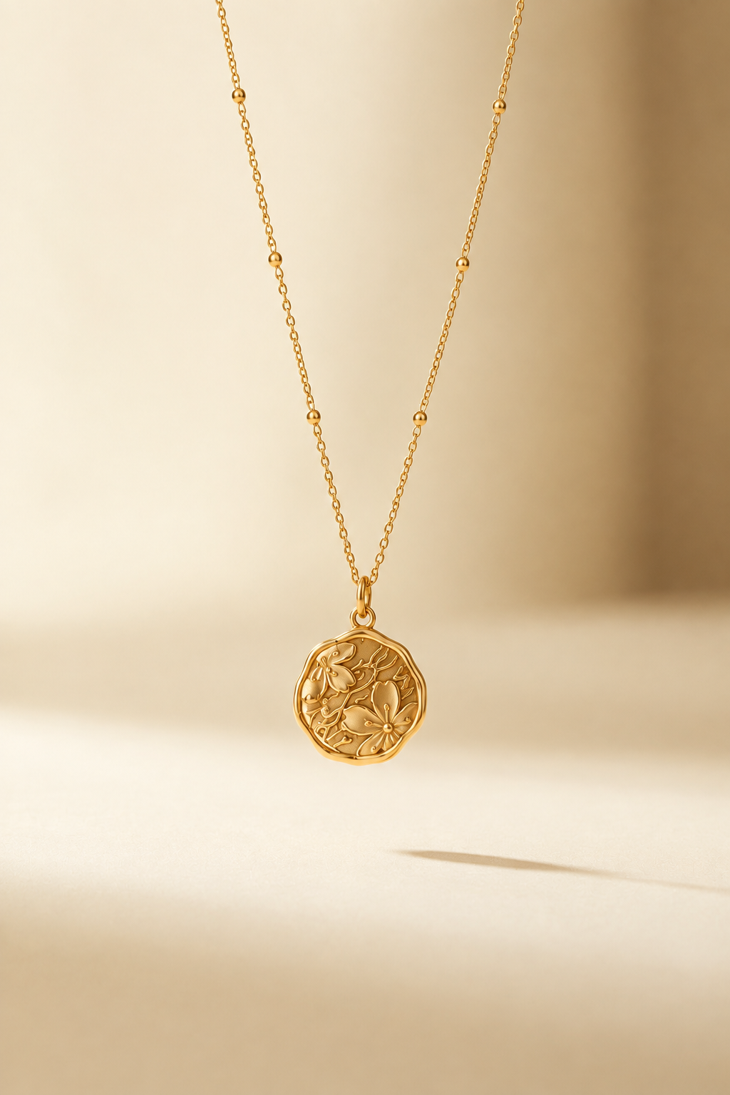 Fiona gold-tone floral medallion necklace on a warm ivory studio backdrop